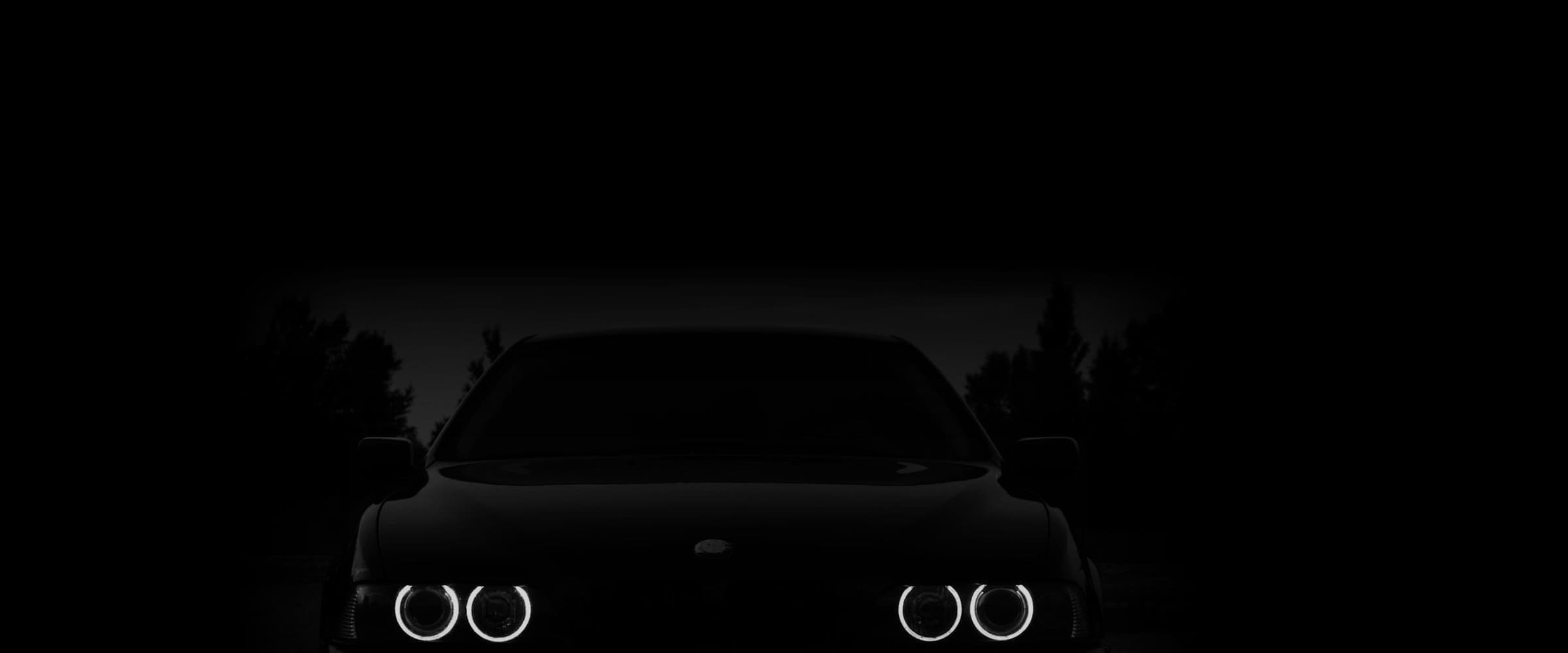 BMW 5 Series with its headlights on in a dark workshop
